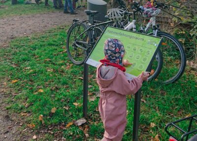 Kind guckt sich eine Informations-Tafel an.