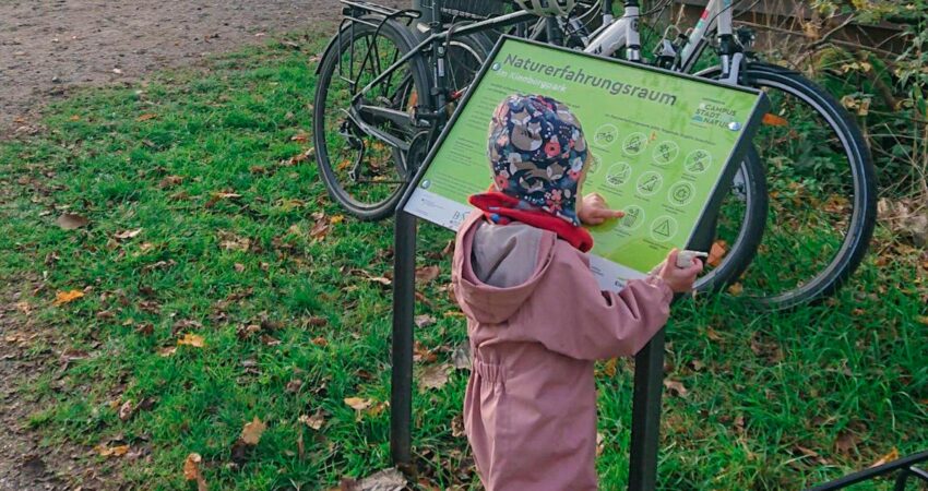 Kind guckt sich eine Informations-Tafel an.