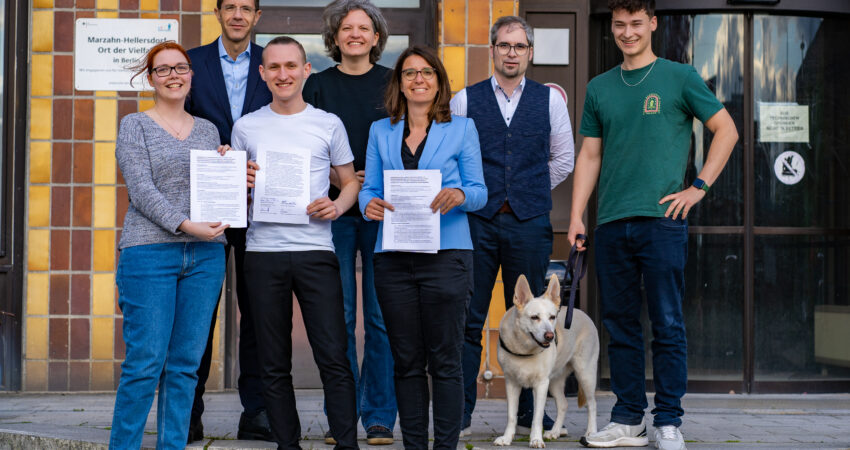 Vertreter*innen von Bündnis 90/Die Grünen und der CDU aus Marzahn-Hellersdorf stehen gemeinsam auf der Treppe vor dem Rathaus Marzahn. In der Hand halten sie eine unterschriebene Vereinbarung. Zu sehen sind: Chantal Münster, Christian Gräff, Max Linke, Maren Tepper, Nadja Zivkovic, Johannes Martin, Pascal Grothe und Hündin Susi.