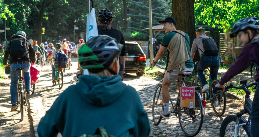 Kinder und Pascal Grothe fahren auf einer Straße mit vielen Bäumen an der Seite.